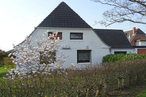 Ein weißes Haus mit einem steilen Satteldach, zwei Fenstern und einem Schornstein.
