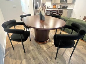 Uma mesa de jantar redonda com um pilar central, rodeada por quatro cadeiras pretas.