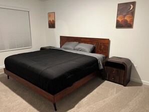 Quarto com estrutura de cama de madeira, mesa de cabeceira e luminária na parede.
