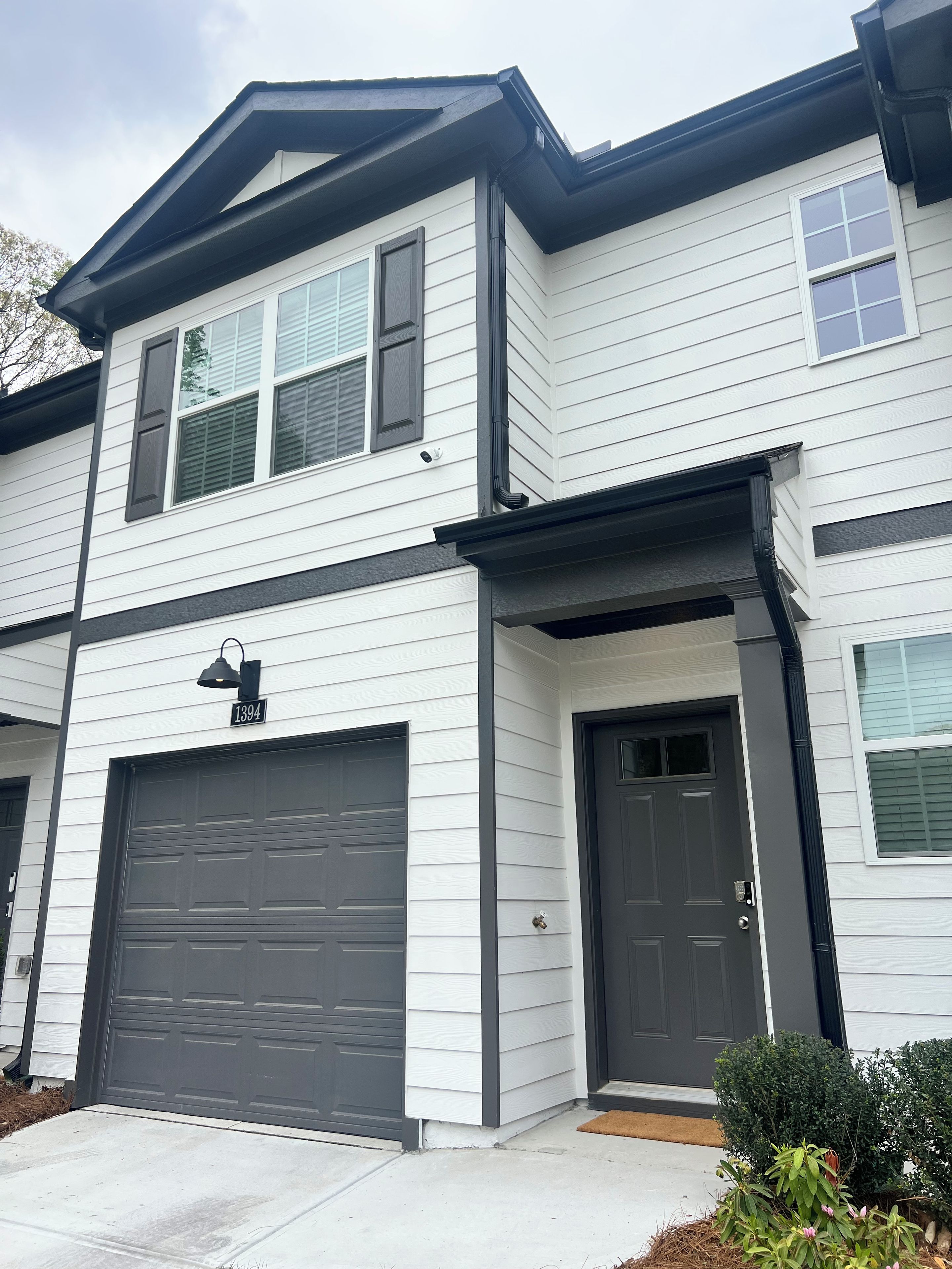 A two-story residential building with a garage, a front door, and a mailbox.