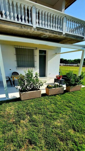 Een modern gebouw met balkon, buitenmeubels en plantenpotten.