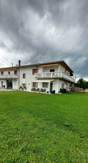 Ein zweistöckiges Gebäude mit Balkon, überdachter Terrasse und gepflegtem Rasen.