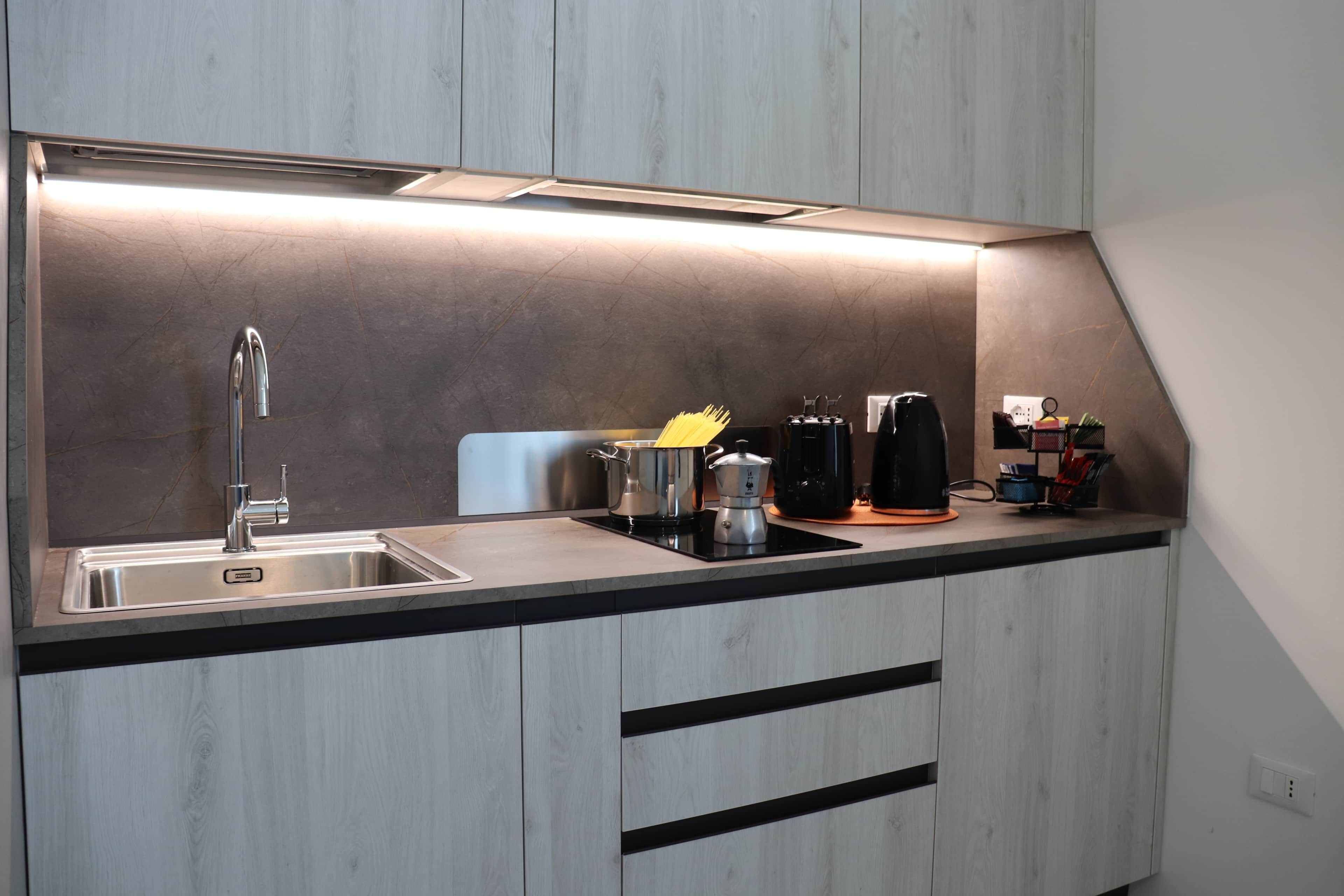 A modern kitchen with a stainless steel sink, a coffee machine, and a kettle.