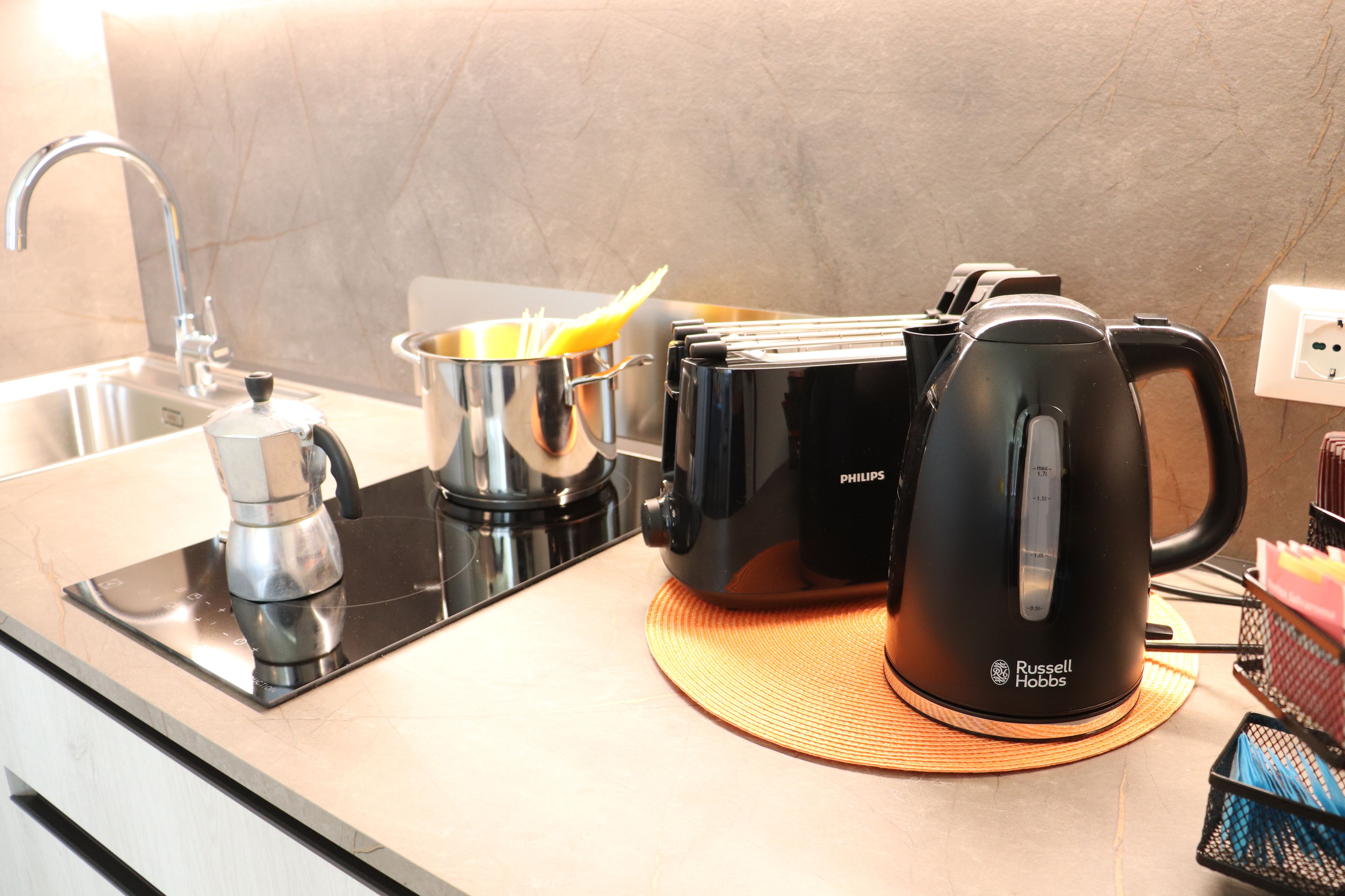 Une cuisine équipée d’une machine à café, d’une casserole et d’une bouilloire sur le plan de travail.