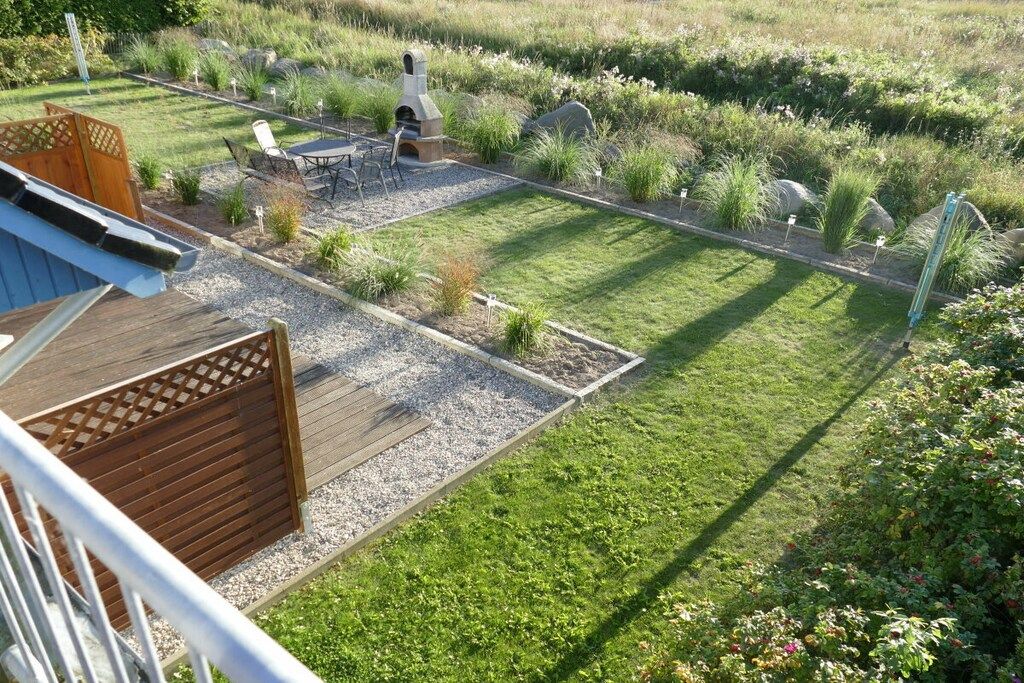 Un jardín bien cuidado con un patio, mobiliario exterior y una chimenea de piedra.