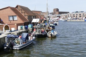 A marina with boats docked, a brick building with a sloped roof, and a clear sky. - maritime house semi-detached house Wismar (Wohlenberg)