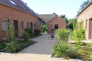Ein Innenhof mit Backsteingebäuden, einer zentralen Statue und einem gepflasterten Weg.