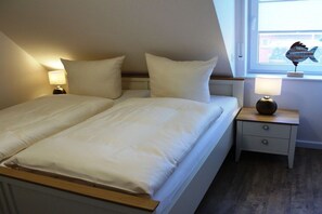 A bedroom with a bed, two bedside tables, and a window. - Holiday home with 2 bedrooms (Greetsiel)