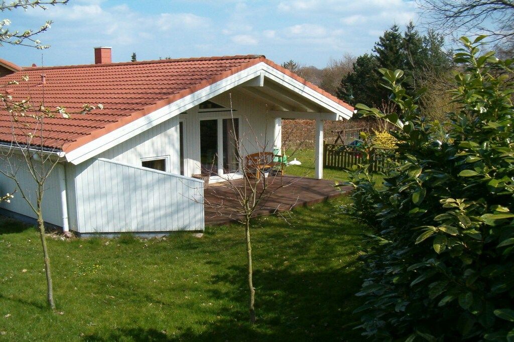 Une maison de plain-pied avec un toit recouvert de tuiles rouges, une véranda et un petit jardin.