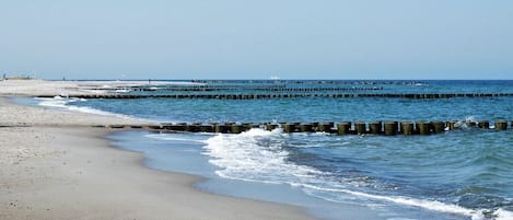 A beach with a wooden breakwater and a clear sky.