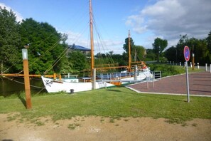 A boat docked at a marina with a grassy area and a paved walkway. - Holiday home with 2 bedrooms (Krautsand)