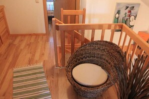 A wooden chair with a woven basket seat and a striped rug on a wooden floor. - Holiday home with 2 bedrooms (Krautsand)
