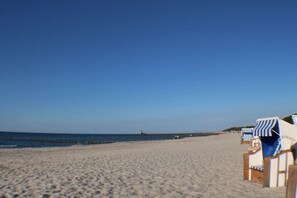 A beach with rows of beach chairs and umbrellas, a clear sky, and a calm sea. - Holiday home with 2 bedrooms (Ostseeheilbad Zingst)
