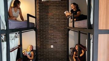 A narrow room with bunk beds, a brick wall, and an air conditioning unit.