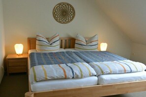 A double bed with striped bedding, two bedside lamps, a wooden headboard, and a decorative wall hanging. - Altschulze "Panorama" (Schwielochsee OT Zaue)