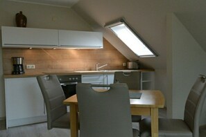 A compact kitchen with a skylight, modern appliances, and a dining area with chairs. - Altschulze "Panorama" (Schwielochsee OT Zaue)