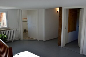 Ein Flur mit Heizkörper, einer Tür zu einem anderen Raum und einer Holztür auf der rechten Seite.