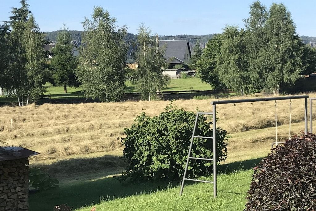 A rural landscape with a stone structure, a metal ladder, and a grassy field.