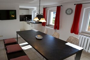 Une cuisine moderne avec un coin repas, une horloge et des rideaux rouges.
