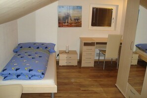 Ein Schlafzimmer mit Bett, Schreibtisch, Stuhl und Fenster.