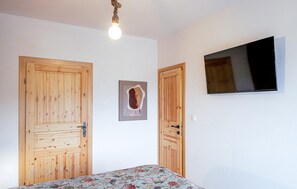 A room with wooden doors, a bed with a floral bedspread, a mounted television, and a light fixture. - 4 bedroom nice home in Jastrebarsko (Dragovanscak)