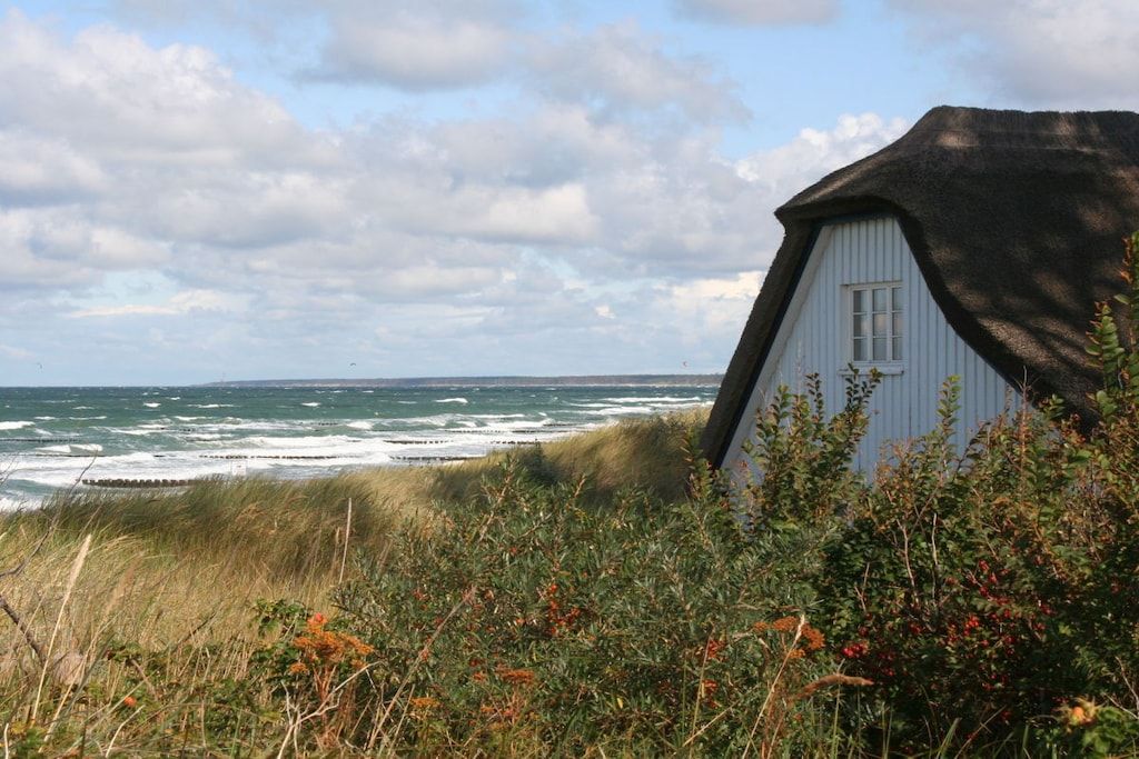 A coastal house with a thatched roof, overlooking the sea.