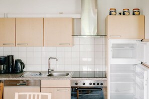 A kitchen with beige cabinets, a white tiled backsplash, a stainless steel sink, a stove, and a refrigerator. - Holiday home with 3 bedrooms (Wieck a. Darß)
