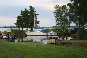 A calm water body with boats docked, surrounded by trees and a grassy area. - Holiday home with 3 bedrooms (Wieck a. Darß)