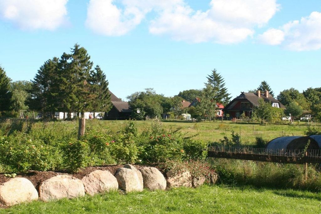 Un paysage rural avec des maisons, un champ clôturé et un ciel dégagé.