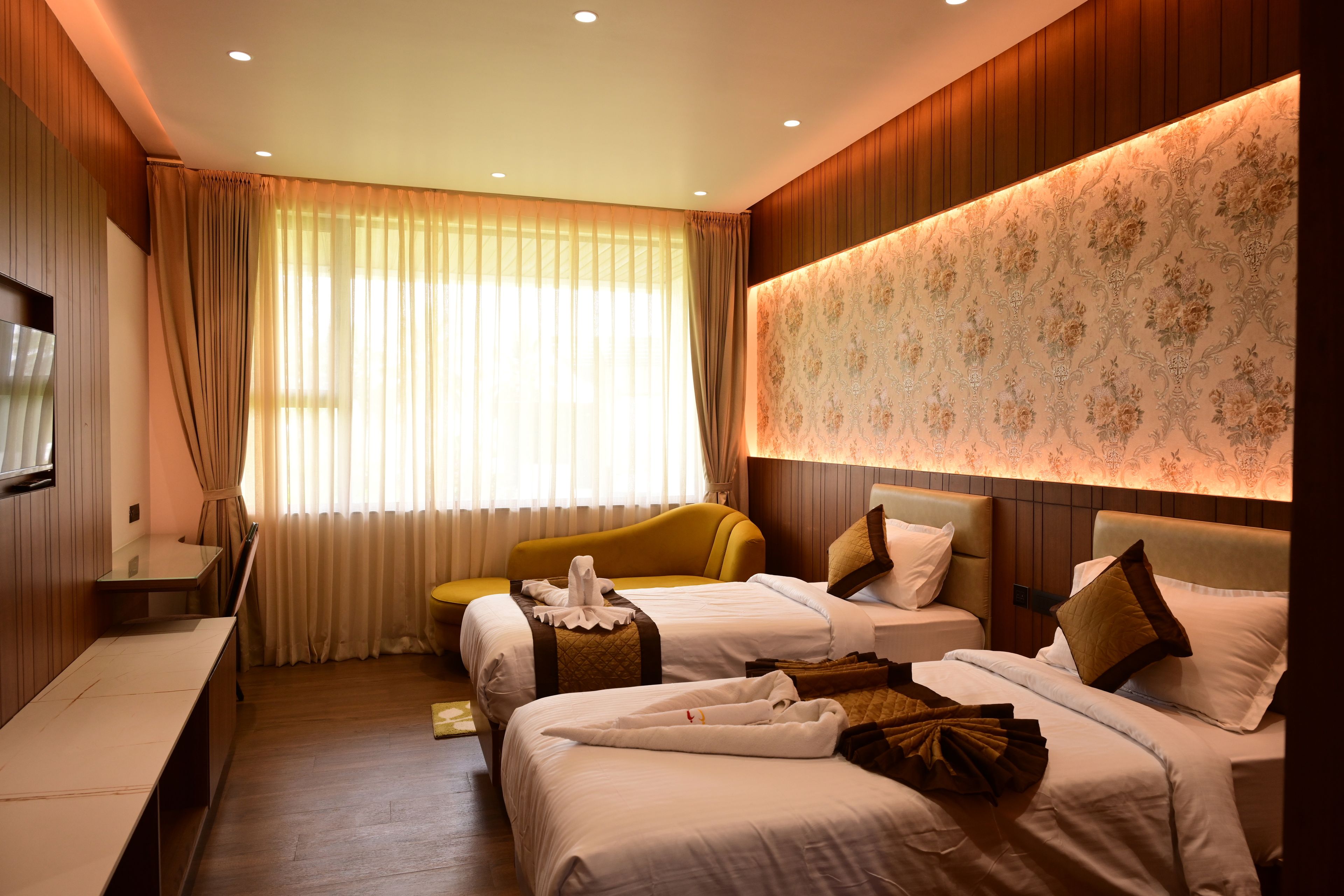Habitación de hotel con dos camas, un escritorio y un ventanal grande con cortinas.