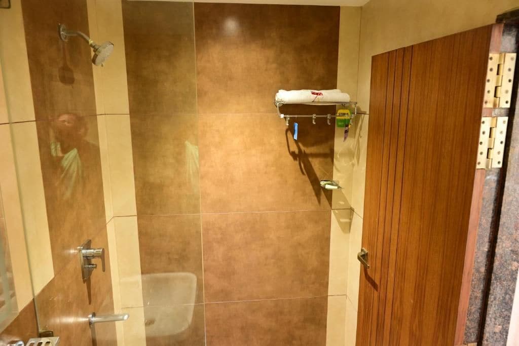 A bathroom with a shower, a towel rack, and a wooden door.