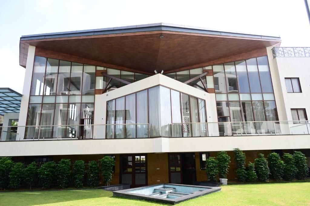 Un edifici modern de dos pisos amb grans finestres, un terrat pla i una piscina al pati.