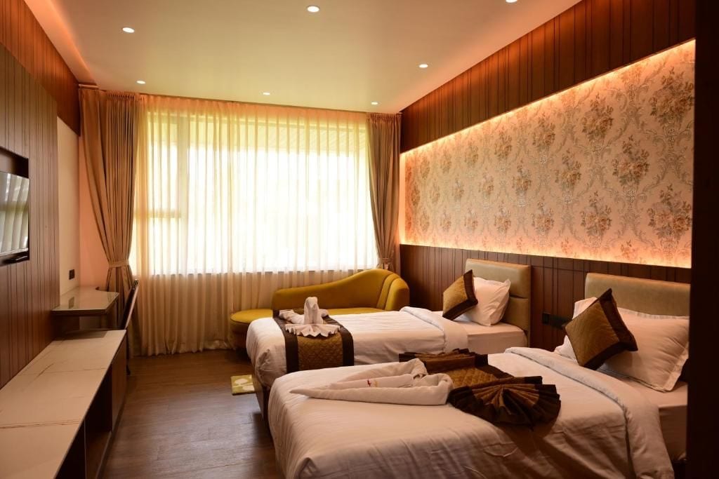 Une chambre d’hôtel avec deux lits, un canapé, un bureau et une grande fenêtre avec des rideaux.