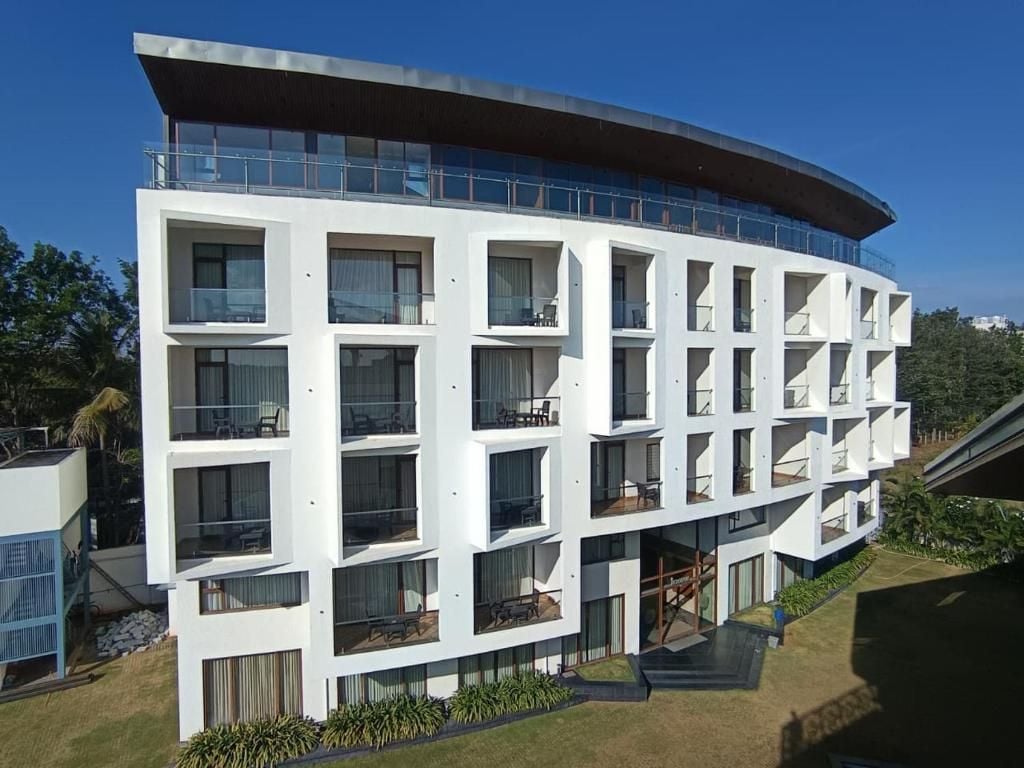 Un edificio moderno de varios pisos con balcones, ventanas amplias y techo plano.