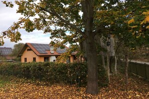 Een huis met zonnepanelen op het dak, omgeven door bomen en een hek.