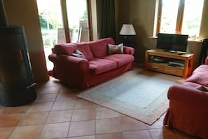 Ein Wohnzimmer mit einem roten Sofa, einem Fernseher auf einem Holzboden und einer Lampe.