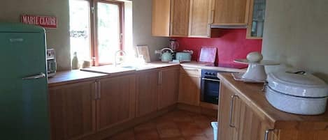 Una cocina con armarios de madera, un fregadero, una estufa y un refrigerador.