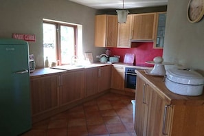 A kitchen with wooden cabinets, a sink, a stove, and a refrigerator. - Holiday home with 3 bedrooms (Laasow\/ Vetschau)