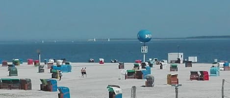 A beach with numerous colorful containers and a clear view of the ocean.