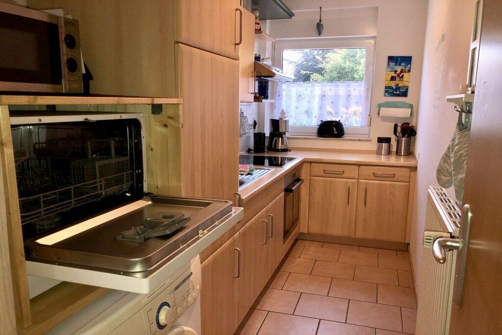 A compact kitchen with a built-in oven, a dishwasher, and a window providing natural light.