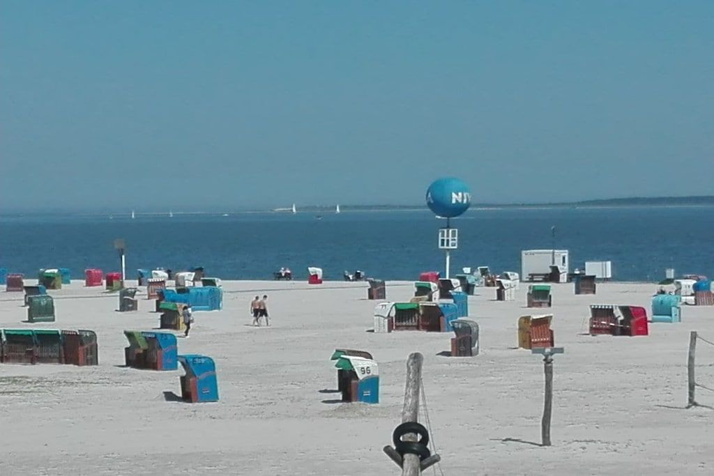 A beach with numerous colorful beach huts and a clear view of the ocean.