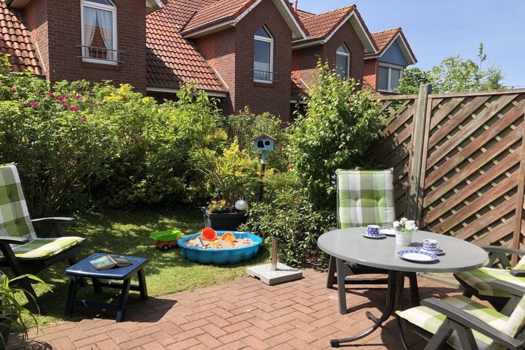 A patio area with a round table and chairs, a small pool, and a birdhouse.