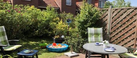 A patio area with a round table and chairs, a small pool, and a birdhouse.