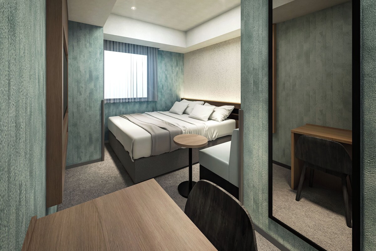 Et moderne hotelværelse med en seng, et rundt bord og en stol.