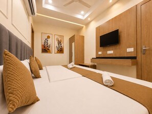 A hotel room with a bed, a television, a desk, and artwork on the wall. - Hotel Signature INN (Vrindavan)