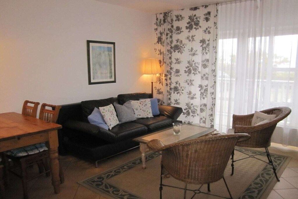 A living room with a sofa, chairs, a coffee table, and a dining table.