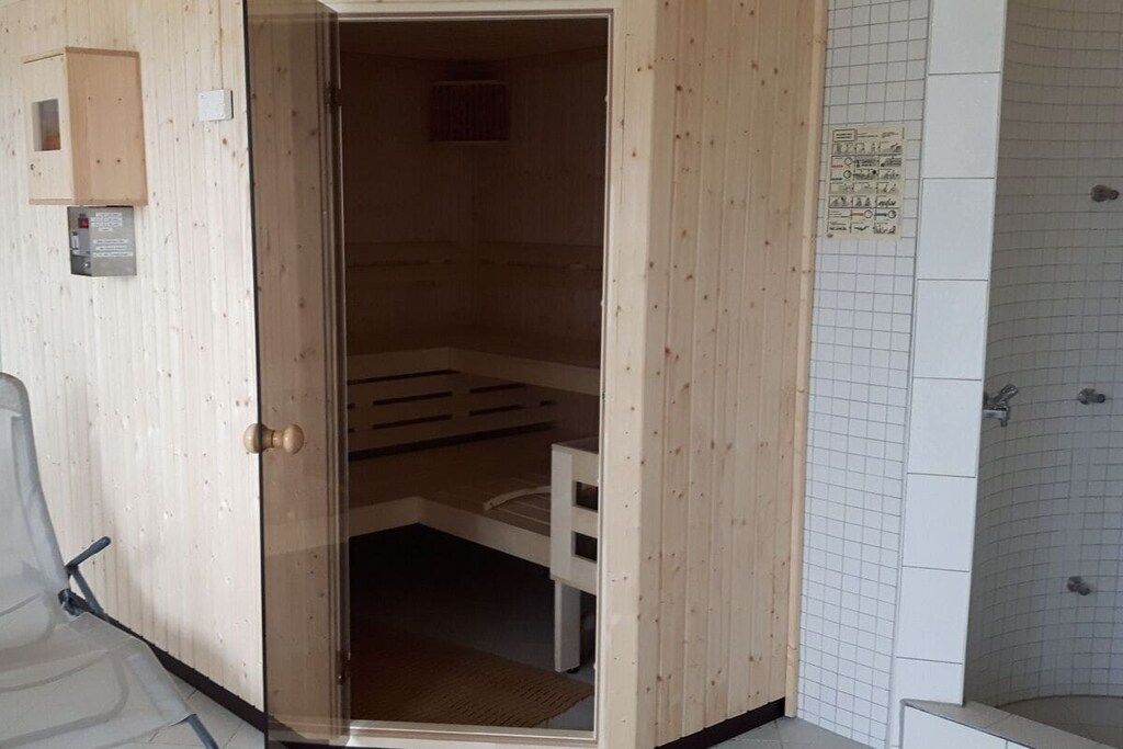 A wooden room with a bench, a door, and a tiled shower area.