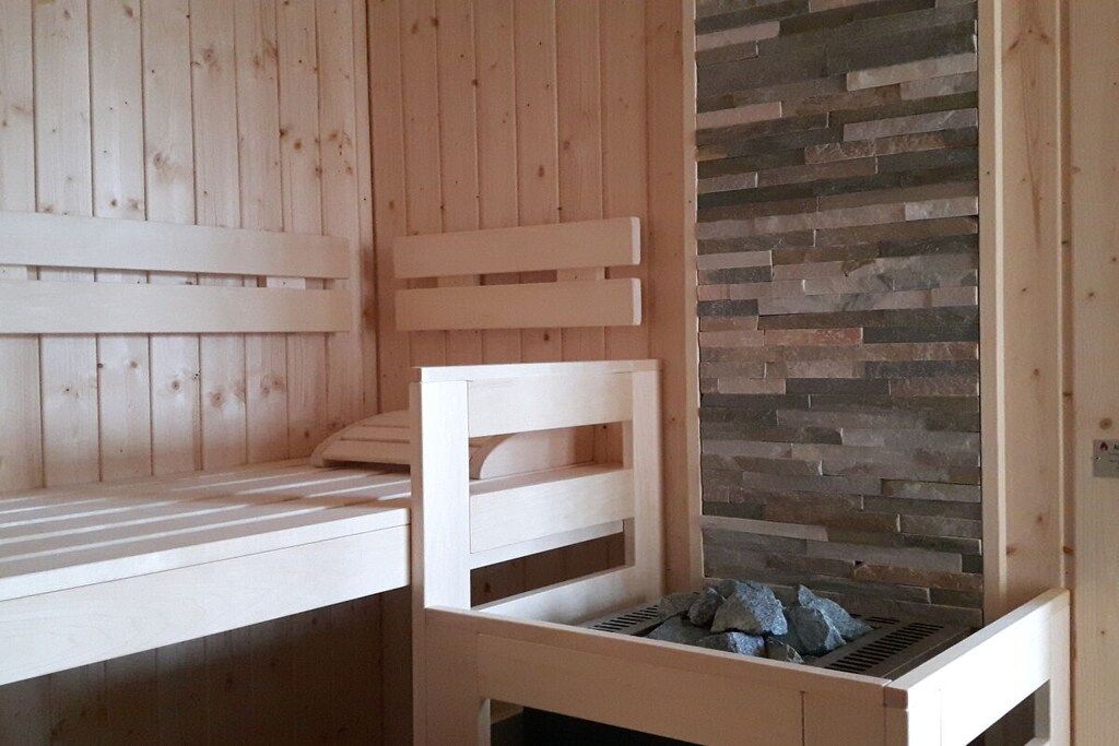 A sauna with wooden benches and a stone wall.