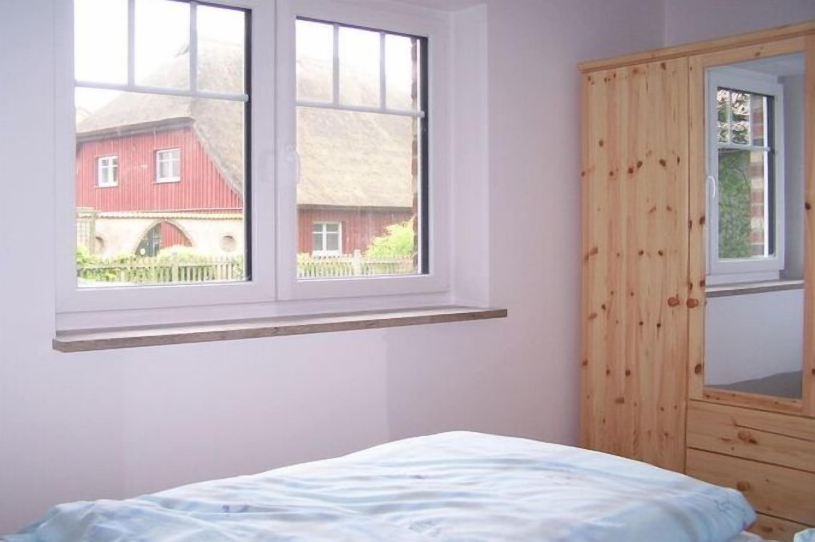 Un dormitorio con una cama, una ventana y un armario de madera.