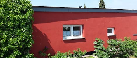 A red building with a window and a small balcony.